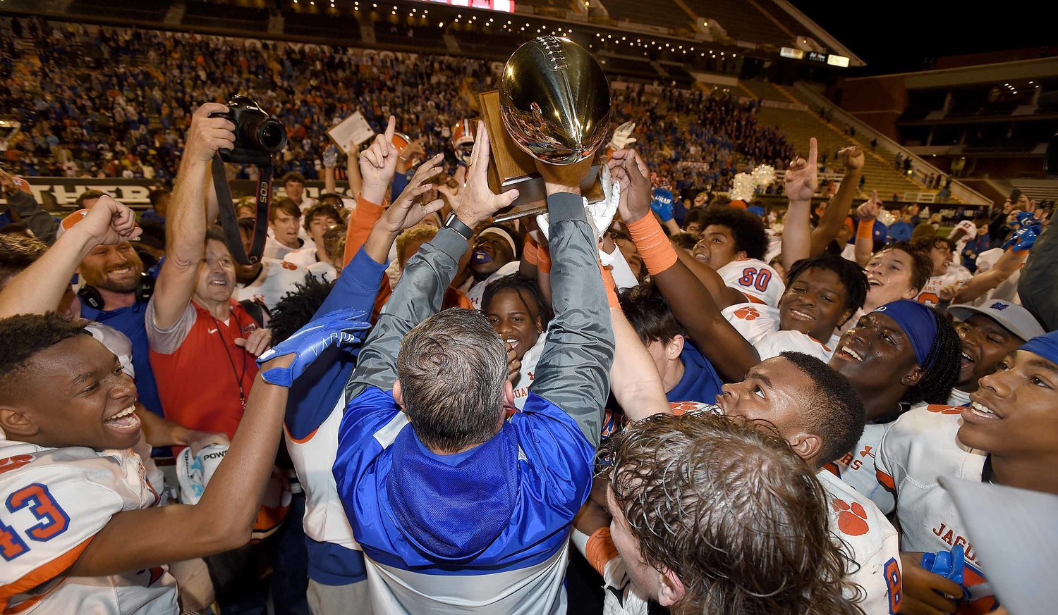 Madison Central head coach Toby Collums hands the trophy to the Jaguars after beating Brandon in the MHSAA Class 6A Football State Championship game at M.M. Roberts Stadium on the University of Southern Mississippi campus in Hattiesburg, Miss., on Friday, December 3, 2021.