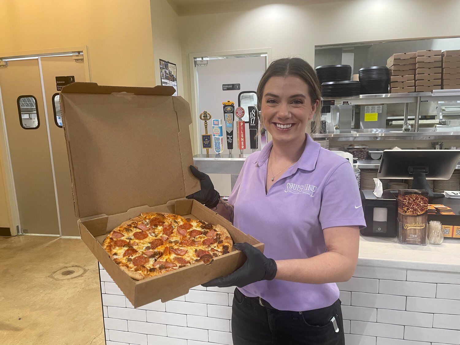 Lauren Leard, general manager for the Gluckstadt location of Soulshine, presents a three meat pizza.